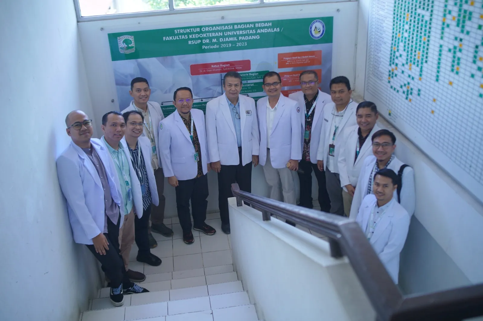 Tim program berfoto di depan bagan struktur organisasi